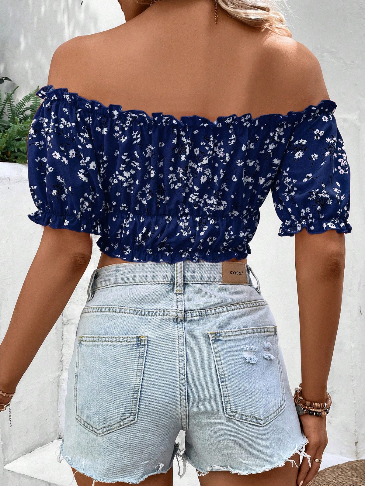 Person wearing a blue floral off-shoulder top and light blue denim shorts.