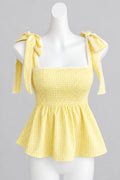 A yellow and white gingham tie-shoulder top displayed on a white mannequin torso against a light gray wall.